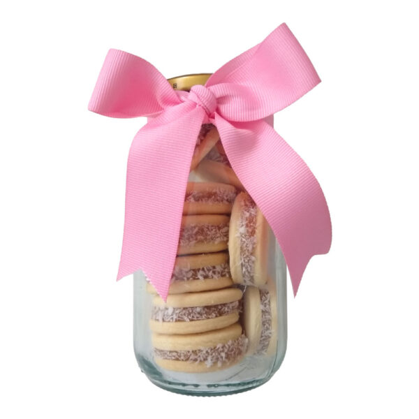 Un contenedor de vidrio co alfajores y una cinta rosada.